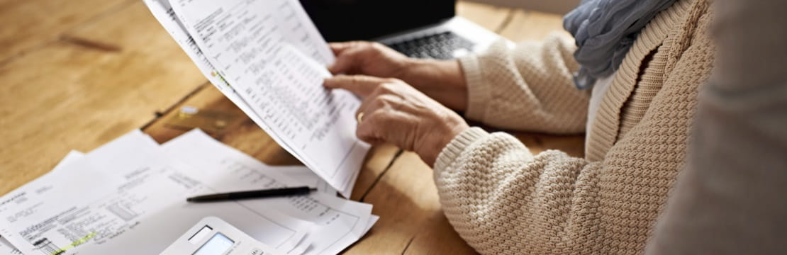 Retirement age woman points to a printed form at a table. 